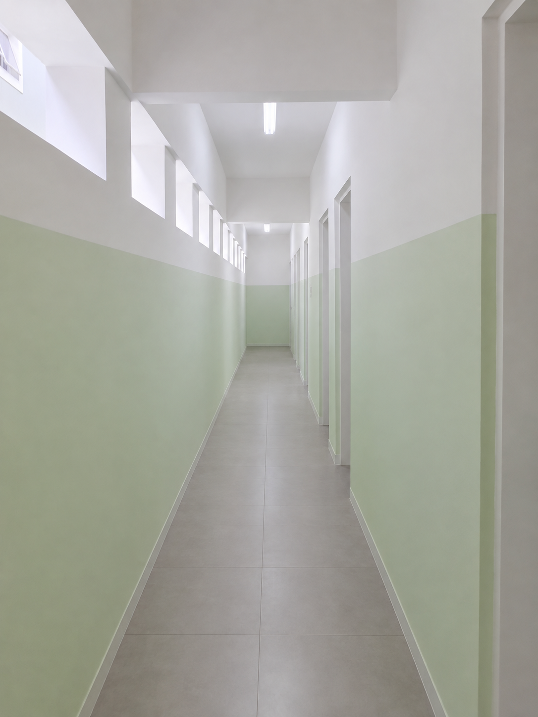 O mesmo corredor depois da reforma, com paredes pintadas em verde e branco, teto novo e iluminação instalada